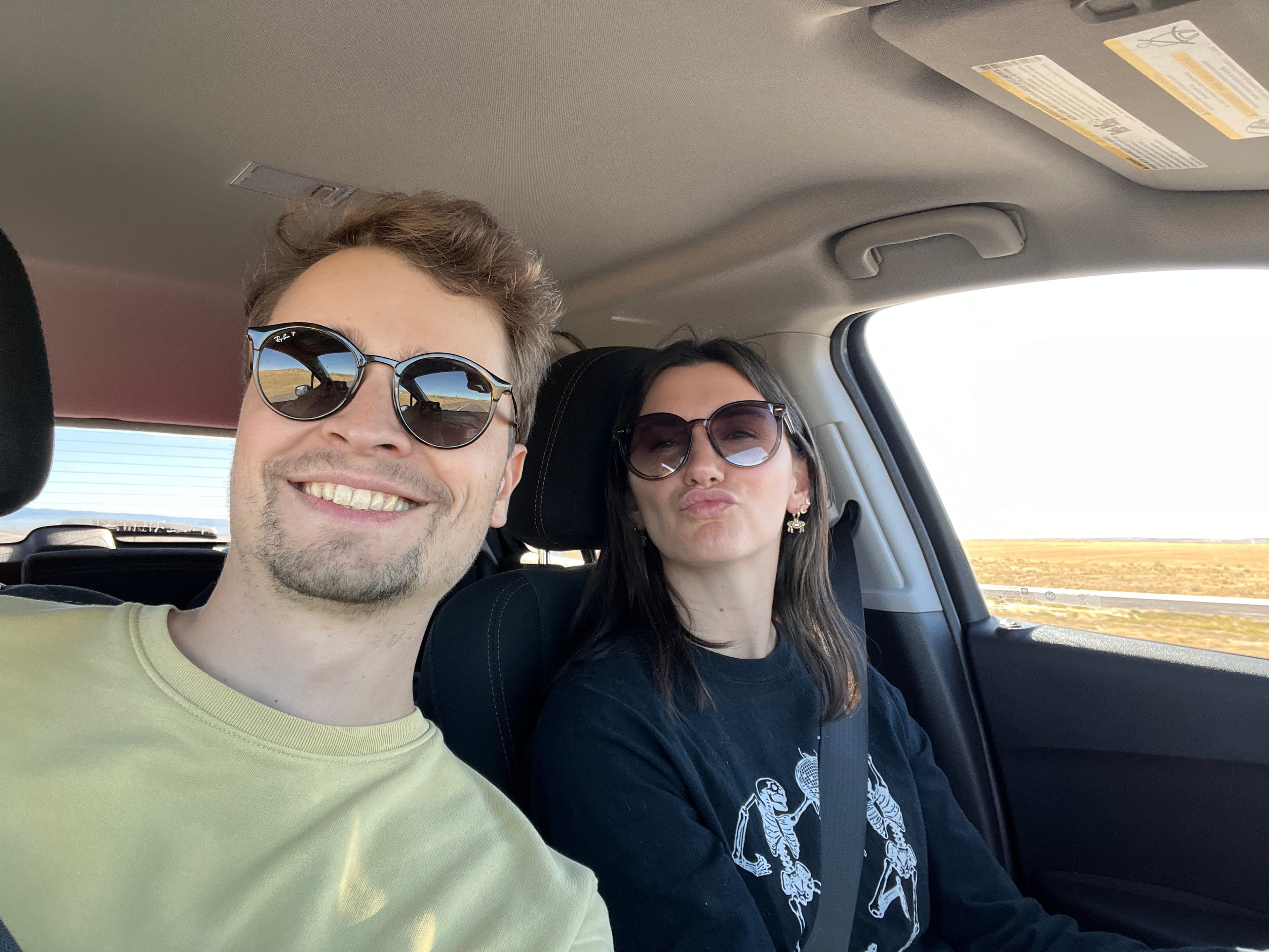 Connor and Jillian take a selfie inside a car. Both are wearing sunglasses and Jillian is making a kissing face